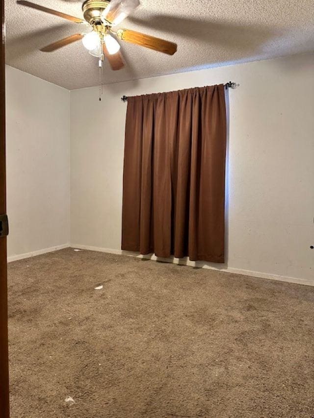 carpeted empty room with ceiling fan and a textured ceiling