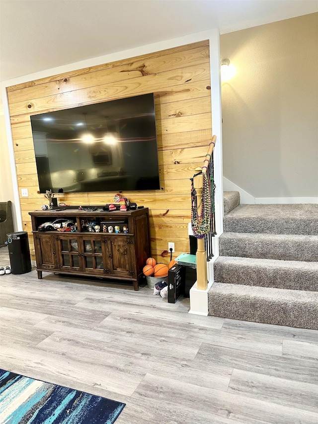 living area with wood walls, stairway, and wood finished floors