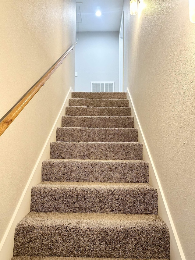 staircase featuring visible vents and a textured wall
