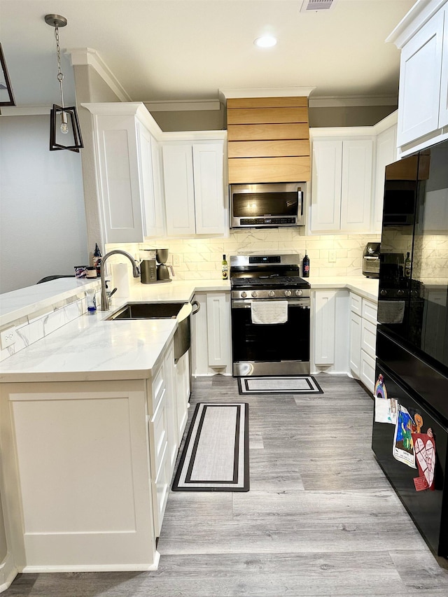 kitchen featuring a peninsula, stainless steel appliances, crown molding, and decorative backsplash