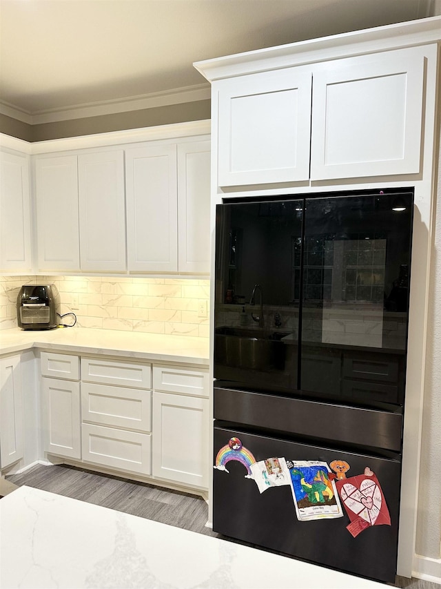 kitchen with light countertops, white cabinets, crown molding, and decorative backsplash