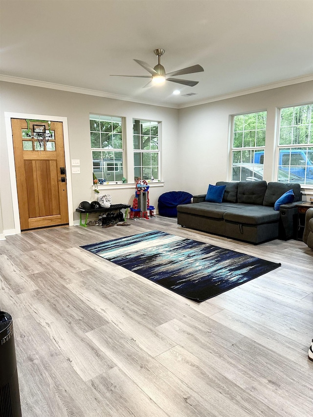 living area featuring ceiling fan, wood finished floors, crown molding, and a wealth of natural light