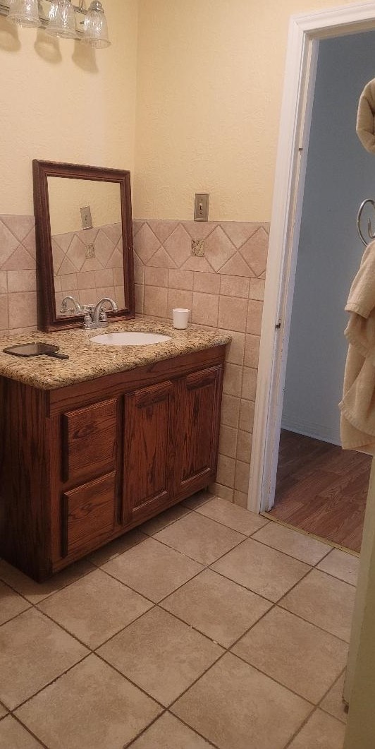 bathroom featuring tile patterned flooring, vanity, and tile walls