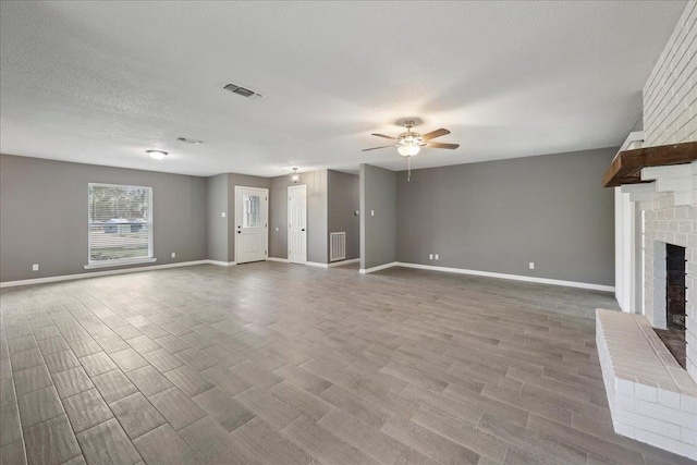 2024 International Ave, Orange, TX 77632 - unfurnished living room featuring a ceiling fan, a fireplace, wood finished floors, and a textured ceiling