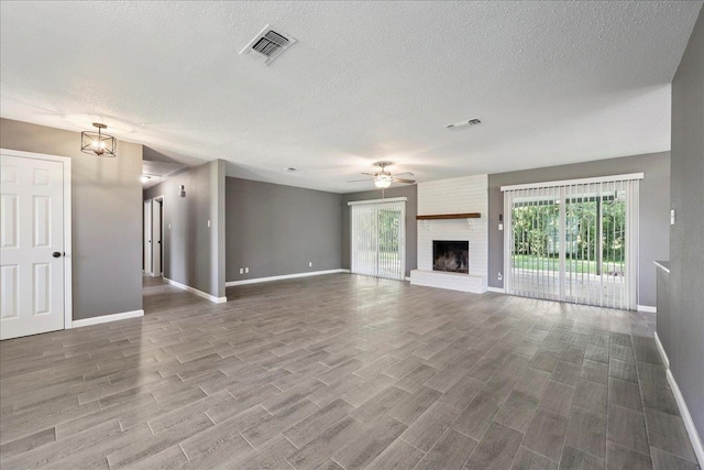 2024 International Ave, Orange, TX 77632 - unfurnished living room with ceiling fan, a fireplace, wood finished floors, and a textured ceiling