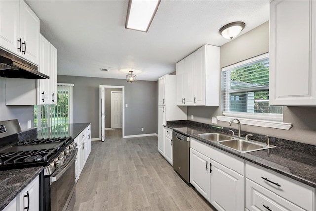 2024 International Ave, Orange, TX 77632 - kitchen with appliances with stainless steel finishes, under cabinet range hood, white cabinets, light wood finished floors, and dark stone countertops