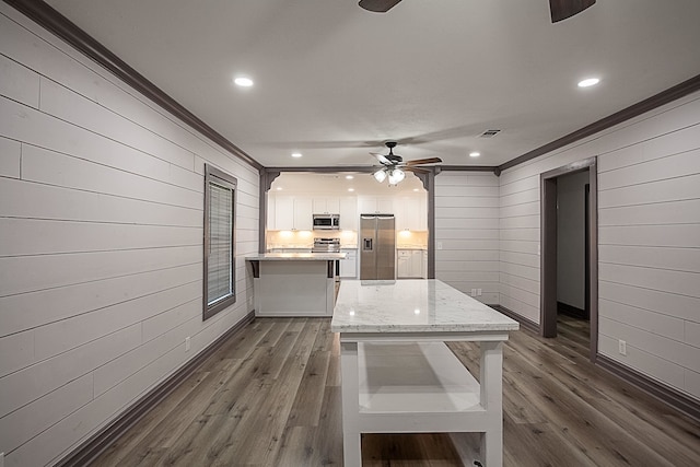 kitchen with stainless steel appliances, dark wood-type flooring, white cabinetry, and crown molding