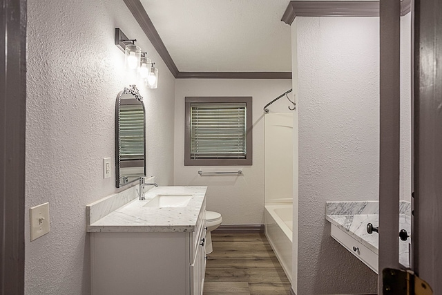 bathroom with a textured wall, toilet, ornamental molding, wood finished floors, and vanity