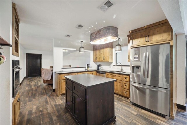 1185 Pinecrest St, Vidor, TX 77662 - kitchen featuring appliances with stainless steel finishes, a sink, dark wood-style floors, a kitchen island, and decorative light fixtures