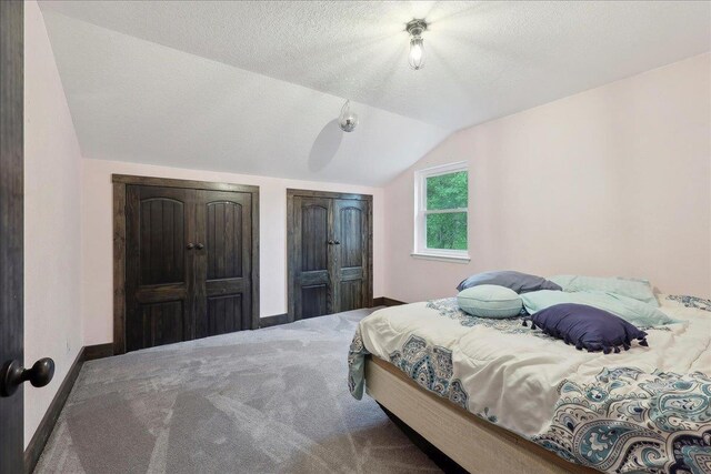 1185 Pinecrest St, Vidor, TX 77662 - bedroom featuring lofted ceiling, carpet, baseboards, two closets, and a textured ceiling