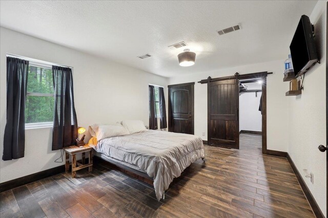 1185 Pinecrest St, Vidor, TX 77662 - bedroom with a barn door, baseboards, and dark wood finished floors