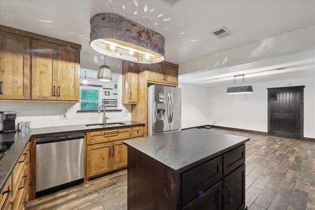 1185 Pinecrest St, Vidor, TX 77662 - kitchen with stainless steel appliances, a sink, dark countertops, dark wood finished floors, and hanging light fixtures