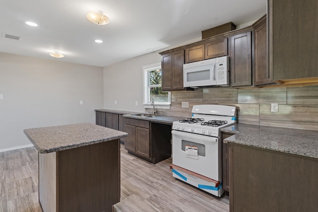 6259 Pat Ave, Port Arthur, TX 77640 - kitchen with white appliances, tasteful backsplash, a center island, dark brown cabinetry, and light wood-type flooring