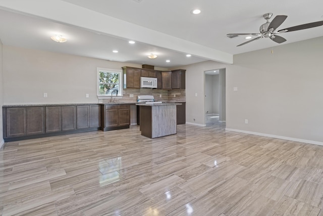 kitchen with ceiling fan, a center island, sink, tasteful backsplash, and stove