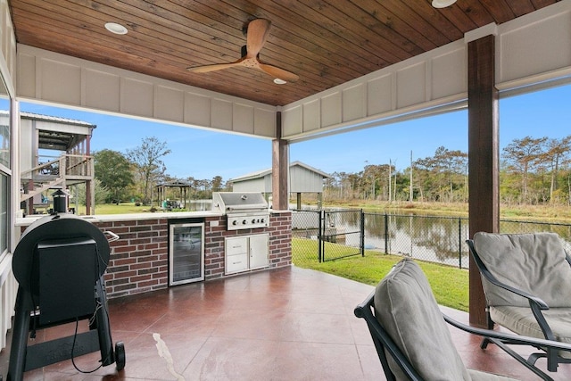 view of patio featuring ceiling fan, an outdoor kitchen, wine cooler, area for grilling, and a water view