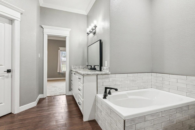 bathroom with wood-type flooring, vanity, tiled bath, and ornamental molding