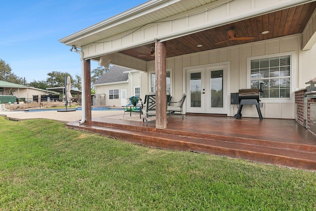 wooden deck with a yard, a patio area, ceiling fan, and french doors