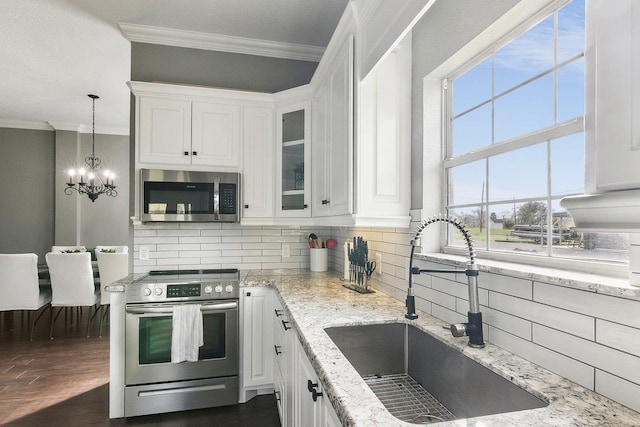 kitchen featuring sink, decorative light fixtures, decorative backsplash, white cabinets, and appliances with stainless steel finishes