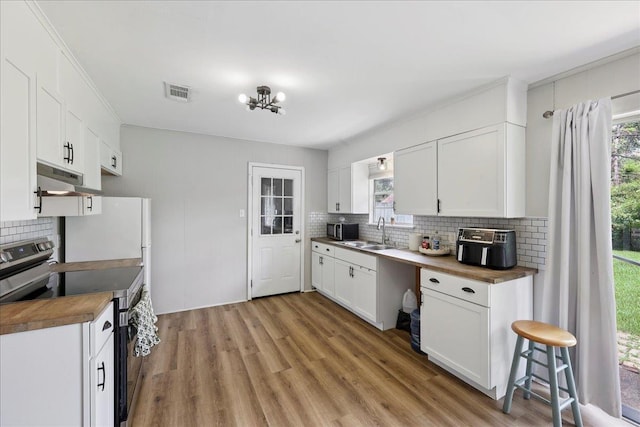 5150 Stardust Dr, Beaumont, TX 77706 - kitchen featuring stainless steel appliances, decorative backsplash, light wood-style flooring, white cabinets, and under cabinet range hood