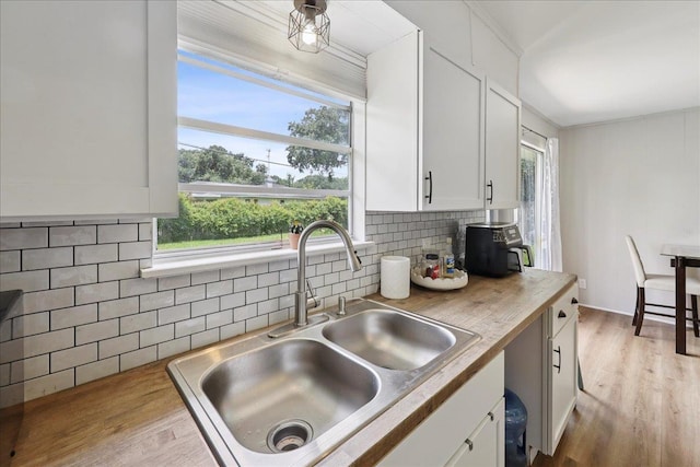 5150 Stardust Dr, Beaumont, TX 77706 - kitchen featuring white cabinetry, plenty of natural light, backsplash, and wood finished floors