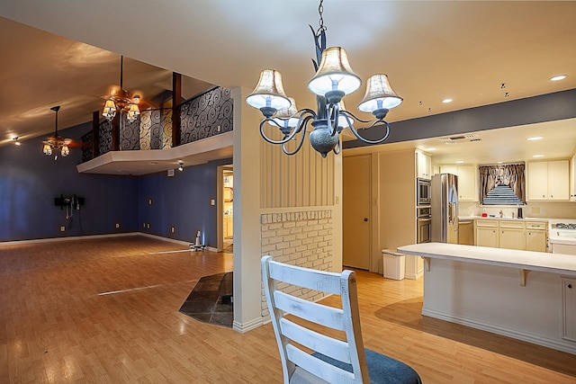 kitchen featuring an inviting chandelier, hanging light fixtures, light hardwood / wood-style flooring, white cabinetry, and stainless steel appliances