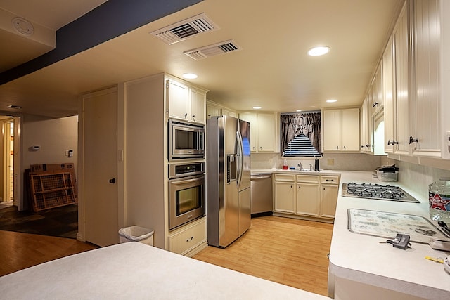 kitchen with light hardwood / wood-style flooring, white cabinets, stainless steel appliances, and sink