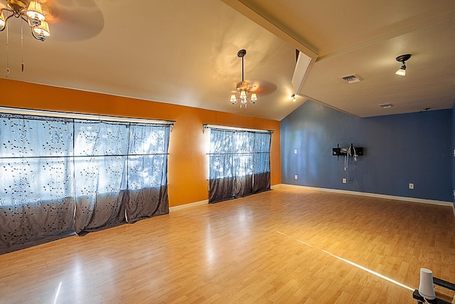 interior space with vaulted ceiling with beams, ceiling fan with notable chandelier, and hardwood / wood-style flooring