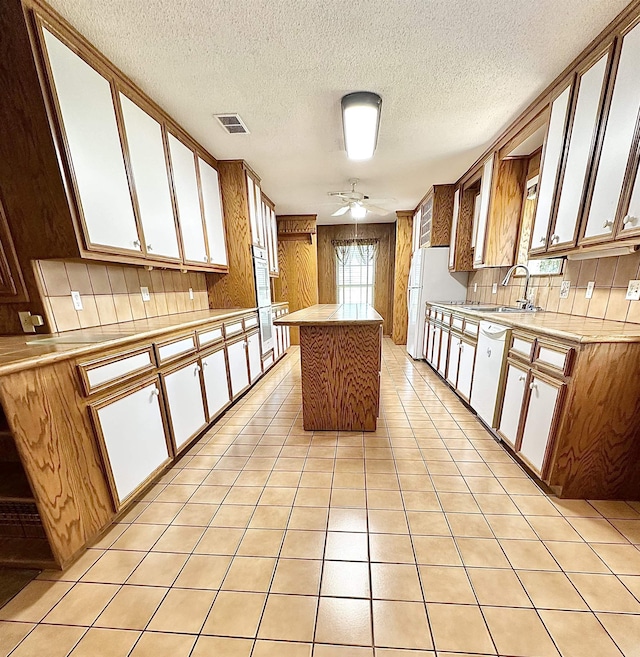 kitchen featuring ceiling fan, a center island, sink, a textured ceiling, and white appliances