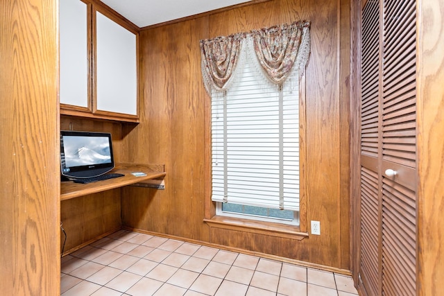 unfurnished office with wooden walls and light tile patterned flooring