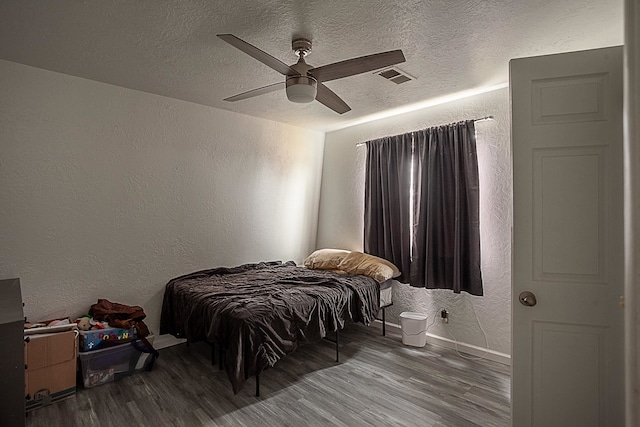 bedroom featuring hardwood / wood-style floors, a textured ceiling, and ceiling fan