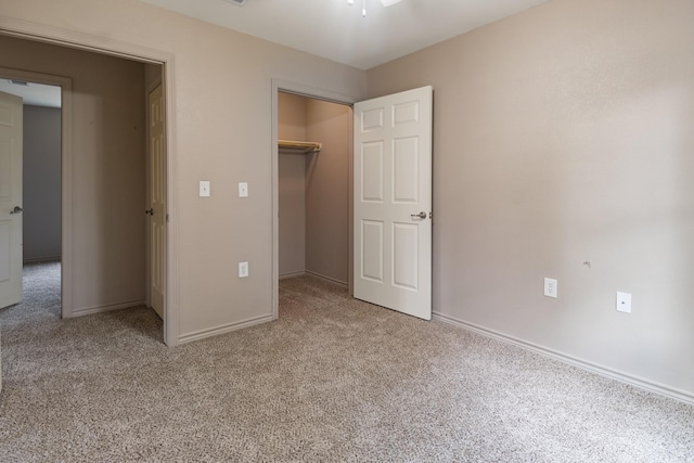 unfurnished bedroom featuring a walk in closet, light carpet, and a closet