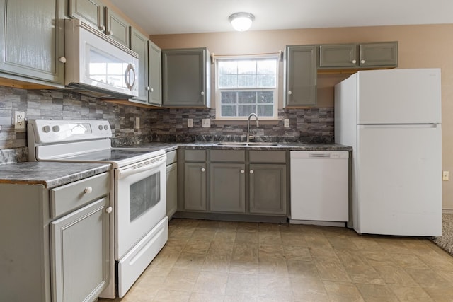 kitchen with backsplash, gray cabinetry, white appliances, and sink