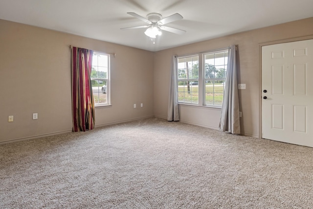 carpeted spare room featuring ceiling fan and a healthy amount of sunlight