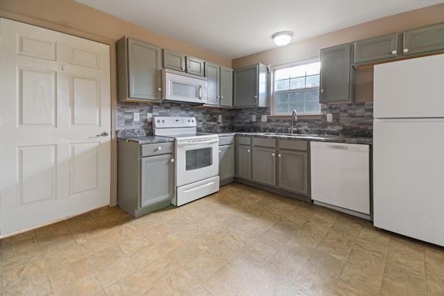 kitchen with gray cabinets, decorative backsplash, sink, and white appliances