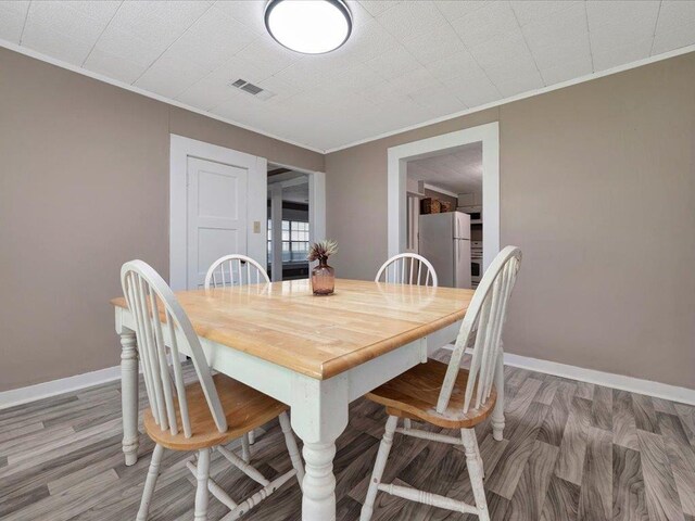 dining area with hardwood / wood-style flooring and ornamental molding