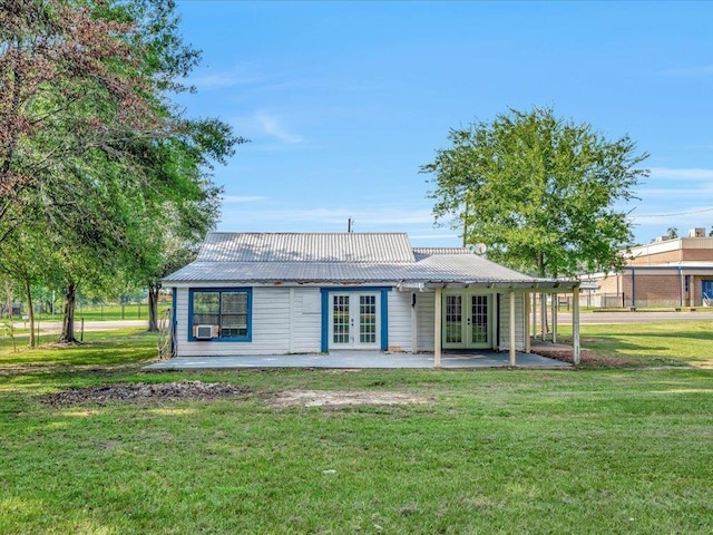 rear view of property with french doors, a patio, and a lawn