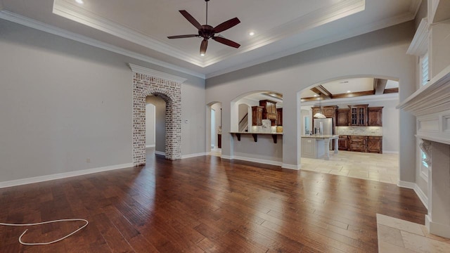 416 Birch View Dr, Lumberton, TX 77657 - unfurnished living room featuring a tray ceiling, a ceiling fan, light wood finished floors, crown molding, and arched walkways