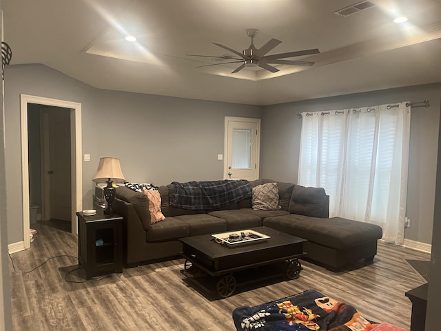 living room featuring lofted ceiling, wood finished floors, visible vents, ceiling fan, and baseboards