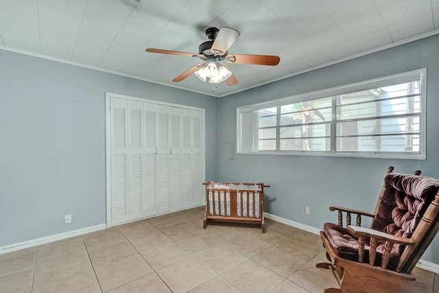 bedroom featuring tile patterned flooring, ornamental molding, a ceiling fan, baseboards, and a closet
