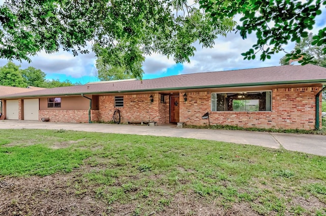 view of front of property with an attached garage, a front lawn, brick siding, and concrete driveway