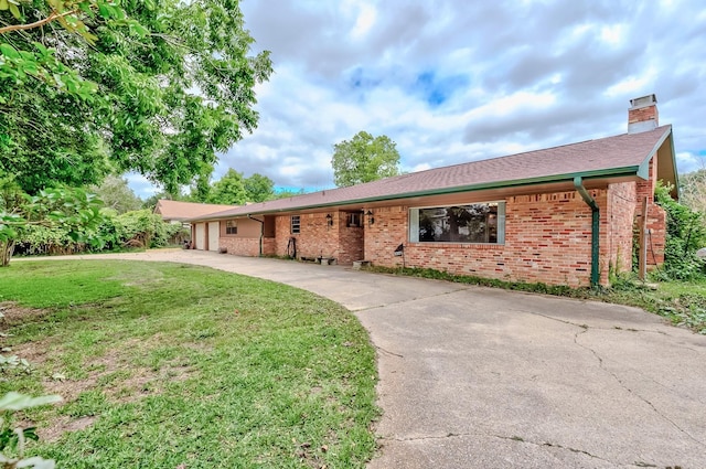 ranch-style home with brick siding, a front yard, a chimney, concrete driveway, and an attached garage