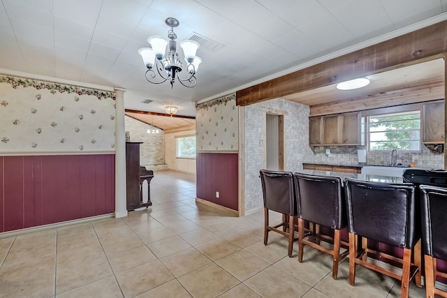 kitchen featuring plenty of natural light, a chandelier, wood walls, light tile patterned floors, and baseboards