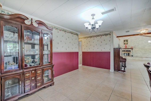 unfurnished dining area with wainscoting, a chandelier, crown molding, tile patterned flooring, and baseboards