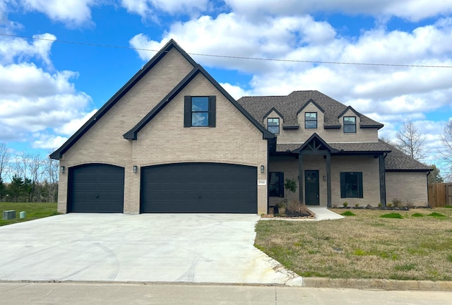 view of front facade featuring a shingled roof, brick siding, driveway, and a front lawn