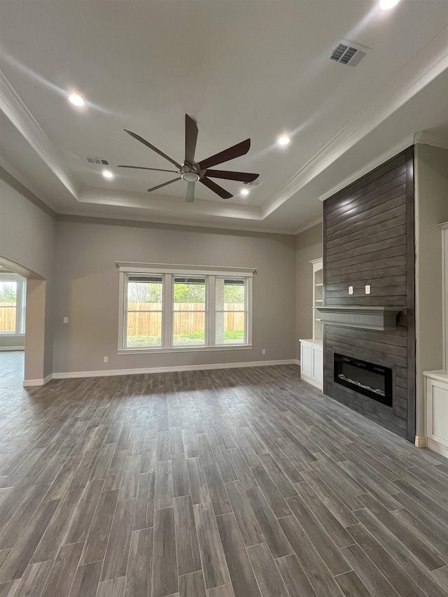 unfurnished living room featuring dark wood-type flooring, a tray ceiling, visible vents, and a fireplace