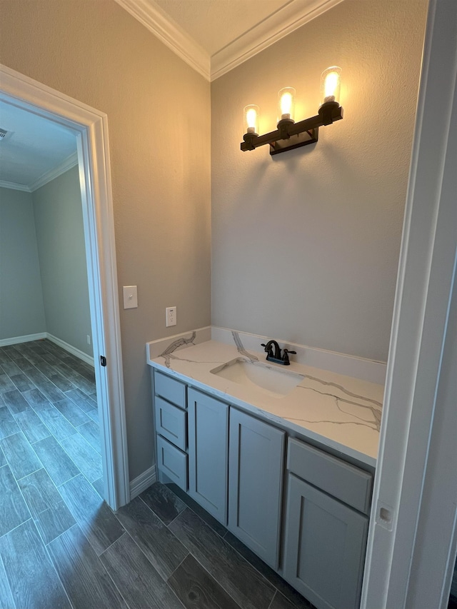 bathroom with visible vents, baseboards, vanity, crown molding, and wood finish floors