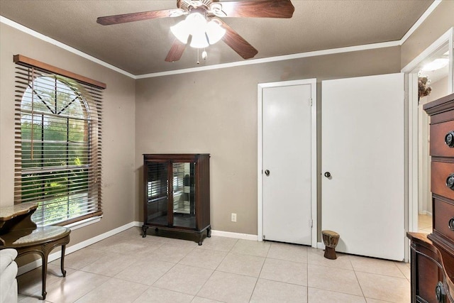 living area featuring ceiling fan, ornamental molding, a textured ceiling, and light tile patterned floors