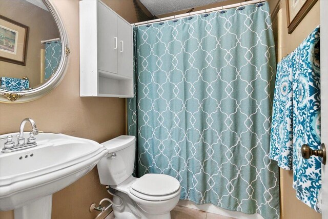 bathroom featuring a textured ceiling, toilet, walk in shower, and sink