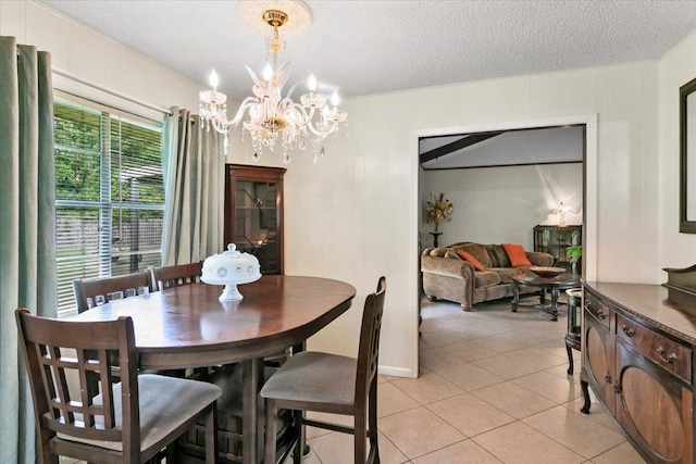 tiled dining space with a textured ceiling and a notable chandelier