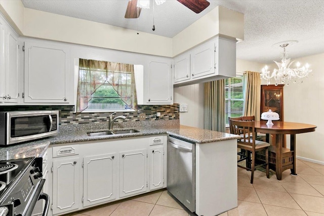 kitchen with white cabinetry, sink, kitchen peninsula, dark stone countertops, and appliances with stainless steel finishes